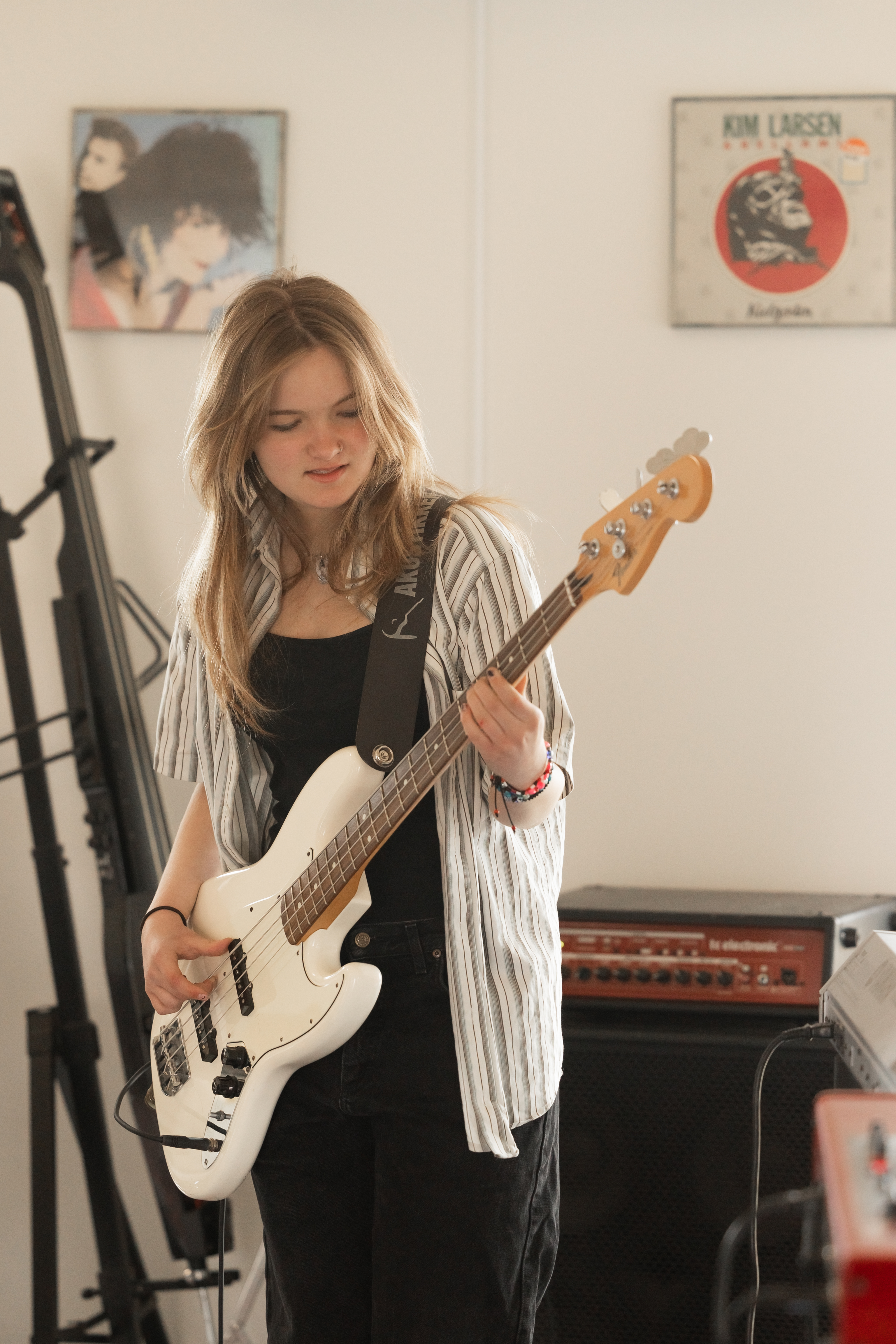 Pige står i musiklokale og spiller guitar 