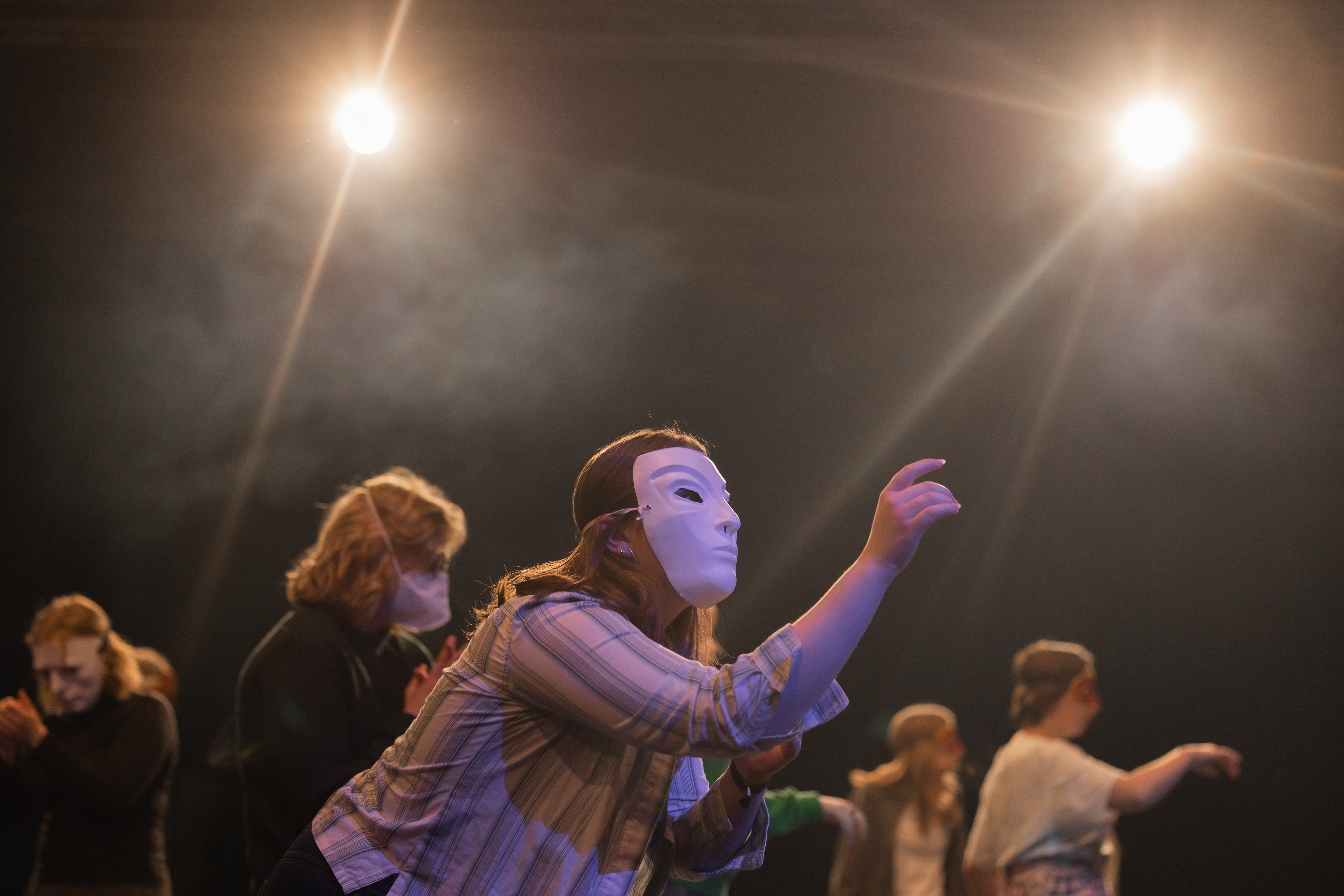 Elev står på scene med maske på